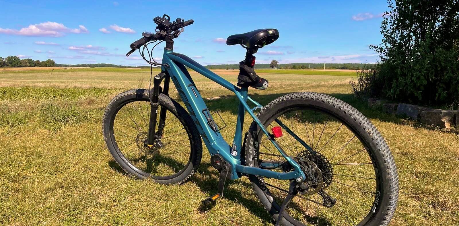 Ein modernes Mountainbike auf einer Wiese mit offenem Himmel im Hintergrund.